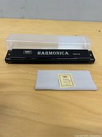 Harmonica, case, cleaning cloth on table