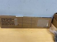 Front of sealed box showing product name, supported TV size, Essentials branding