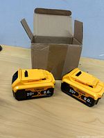 Two 20V 8.0Ah lithium batteries beside shipping box