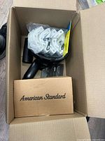 Top view of open box showing American Standard box, white plastic fittings, black bottle