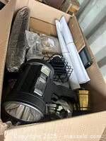 Overview of box with cylindrical light, wire cage, rolled sheets and other items