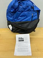 Folded blue and black pop-up tent with instruction sheet
