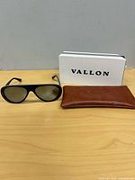 Sunglasses, brown pouch, white Vallon box on table