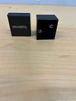 Front view of two silver stud earrings displayed in Specmental box