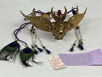 Full view of Egyptian headpiece with cords, gemstones, feathers and information tag
