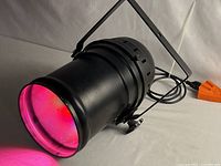 Side view of black PAR can with pink light output visible, showing yoke bracket and power cord