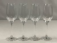 Front view of four identical Riedel crystal glasses standing in a row