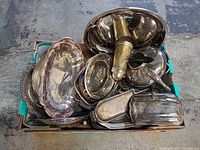 Box filled with assorted silver-plated serving pieces