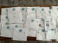 Overview of multiple packaged silver initial necklaces on table