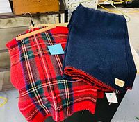 Overall view of navy blanket and red plaid throw on table