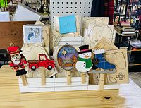 Front view of ornament blanks in white stand, sample painted pieces clipped in front