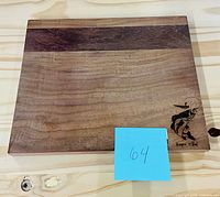 Top view of hardwood cutting board displaying two-tone wood and engraved fish logo