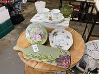 All items grouped on round table including stool, cutting board, plates, milk glass snack sets, green vase