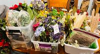 Overview of three tubs filled with mixed faux flowers, greenery and dried grasses