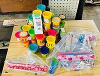 Stacked Play-Doh mini tubs and two bags of slap bracelets displayed on wooden surface