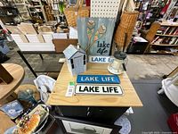 Overview showing Lake Life paddle sign, metal plate signs, house block, glass lantern, cookie jar