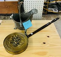 Coal scuttle bucket and brass bed warmer displayed on tabletop
