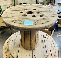 Full view of wooden cable spool on top of larger spool, showing size and condition
