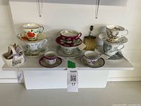 Shelf with all tea cups, saucers, basket and brush visible