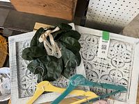 Lot overview showing two white framed faux tin tiles, green magnolia wreath and pastel wooden hangers