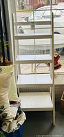 Full view of white ladder shelf showing four shelves