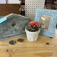 Front view of wooden birdhouse box, pewter dishes, planter, frame