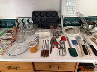 Group shot of entire lot on countertop showing hand mixer, pans, bowls, utensils
