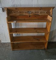 Front view of pine bookshelf showing shelves, integrated peg rack and heart cut-out