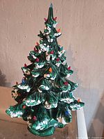 Front view of ceramic Christmas tree showing snow accents and multicolored pin lights