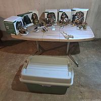 Full lot with six boxed buildings, accessories spread on table, storage bin on floor