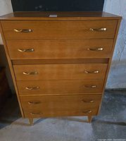 Front view of six-drawer wood veneer highboy dresser showing overall design and brass-tone handles