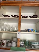 cabinet view showing soup crocks, glasses, mugs, plates and bowls