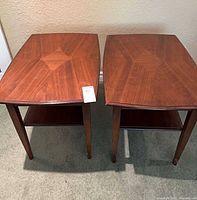 Two matching wood veneer end tables front view showing overall form and shelves