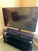 Front view of Sony TV on glass stand with soundbar