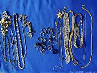 Overview of necklaces and rings arranged on blue fabric