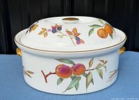 Side view showing fruit motif, gold handles and lid design
