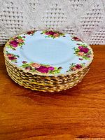 Stack of eight rose-pattern plates showing gold rims