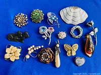All fifteen brooches laid out on blue background