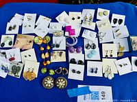 All earrings laid out on blue background full view