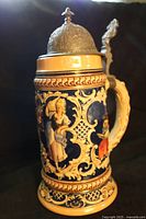 Front view of stein showing cobalt relief scenes and pewter lid