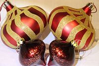Group shot of all four ornaments: two large red/gold glitter, two small burgundy/gold fleck