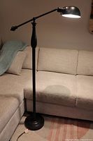 Full view of floor lamp next to sofa, light on