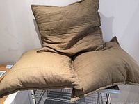 Three quilted square cushions stacked on wire shelf