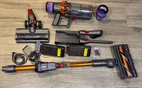 Entire set laid out on floor showing vacuum body, wand, cleaner heads, attachments, batteries, chargers, filter, gaskets