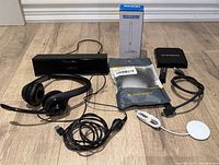 All items laid out on floor: headset, Bluetooth speaker, Qi charger, HDMI cable pack, TV antenna box, Skystream box, HDMI dongle