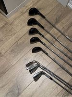 Eight clubs arranged on floor showing woods and irons