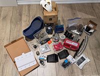overall view of assorted hardware, overshoe, drill bits, wheel chocks, shower filter, lighting bars, lockout kit, curtain rods boxes