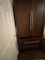 Front view of dark wood armoire with two doors and two drawers