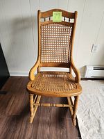 Front view of wooden rocking chair showing cane backrest and seat