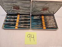 Both open Carvel Hall cases showing all knives and forks
